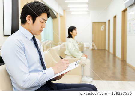一位商人正在醫院候診室填寫醫療問卷。 139227550