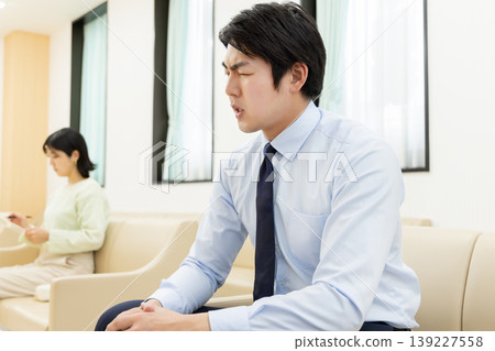 候診室裡，一位生病的商人正在接受治療；一位女士正在填寫醫療問卷。 139227558