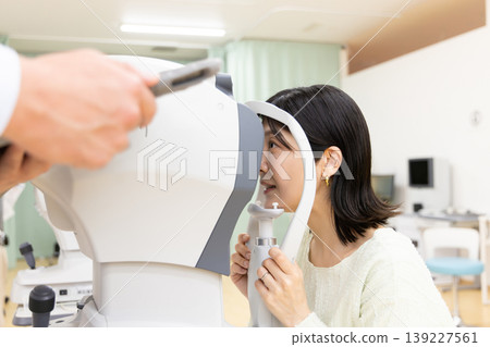A woman undergoing an eye exam at an ophthalmologist's office. A woman undergoing an eye exam at an ophthalmologist's office. 139227561