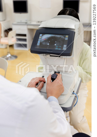 A scene of a doctor and patient undergoing a vision test at an ophthalmology clinic. 139227569