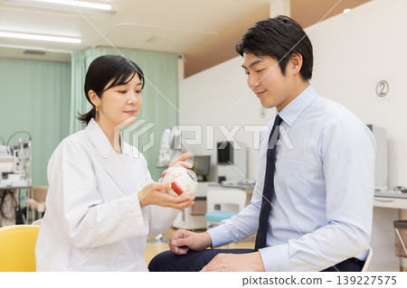 一位女醫生正在為一位病人進行問診,醫生用眼球模型進行講解。 一位女醫生正在為一位病人進行問診,醫生用眼球模型進行講解。 139227575