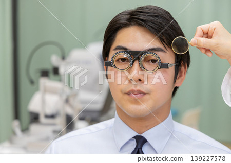 眼科檢查的特寫鏡頭,醫生正在使用試鏡架調整鏡片。 眼科檢查的特寫鏡頭,醫生正在使用試鏡架調整鏡片。 139227578