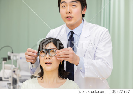 眼科醫師使用試戴架為一名女患者進行視力檢查。 眼科醫師使用試戴架為一名女患者進行視力檢查。 139227597