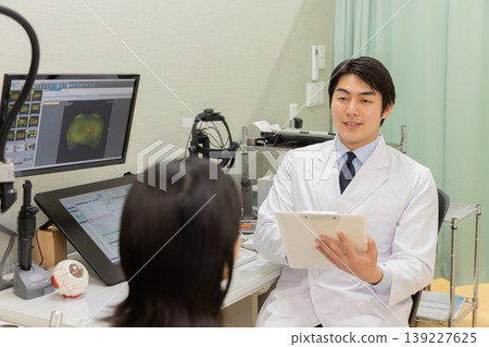 眼科醫生在問診期間向患者解釋檢查結果的場景（顯示器是檢查螢幕）。 139227625