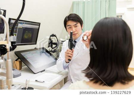 醫療檢查場景，眼科醫生用手電筒檢查女病人的眼睛（顯示器是測試螢幕）。 139227629
