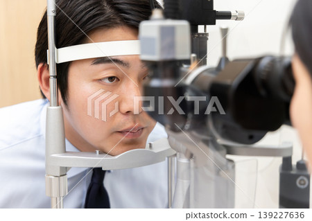 畫面中,一名男性患者正在眼科診所接受裂隙燈眼科檢查,他的醫生正在旁邊。 畫面中,一名男性患者正在眼科診所接受裂隙燈眼科檢查,他的醫生正在旁邊。 139227636