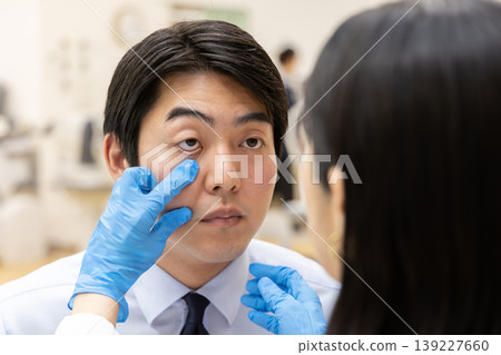 眼科醫師診間進行眼部檢查的場景:醫師正在檢查眼瞼。 眼科醫師診間進行眼部檢查的場景:醫師正在檢查眼瞼。 139227660