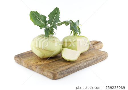 Fresh kohlrabi vegetables with green leaves on a rustic wooden cutting board 139228089