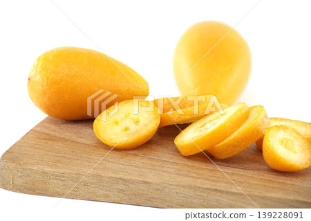 Fresh kumquats sliced and whole on a wooden board, bright and vibrant Fresh kumquats sliced and whole on a wooden board, bright and vibrant 139228091