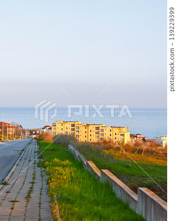 Modern residential block overlooking the sea and a grassy slope. 139229399