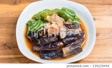 Grilled eggplant and bell peppers marinated in Japanese-style broth. A side dish of summer vegetables marinated in Japanese-style broth. Wood grain background. 139229444