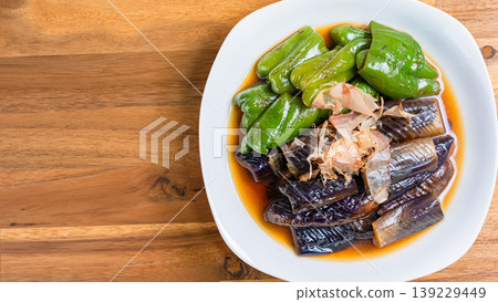 Grilled eggplant and bell peppers marinated in Japanese-style broth. A side dish of summer vegetables marinated in Japanese-style broth. Wood grain background. 139229449