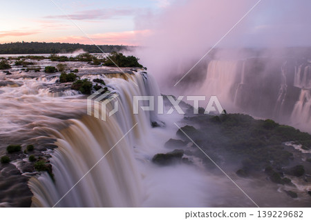 Dramatic landscape of iguazu falls flowing water mist and peaceful dawn sky 139229682