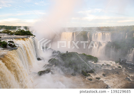 Majestic breathtaking iguazu falls cascade over lush green cliff creating thick white mist Majestic breathtaking iguazu falls cascade over lush green cliff creating thick white mist 139229685