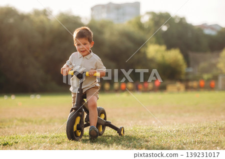 Boy is driving the little bicycle on the field under sunlight Boy is driving the little bicycle on the field under sunlight 139231017
