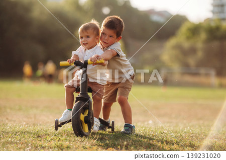 Learning to ride. Kids are playing with bicycle on the field Learning to ride. Kids are playing with bicycle on the field 139231020