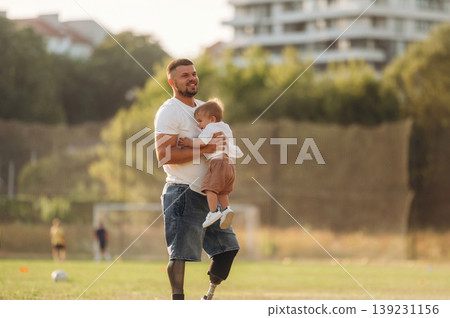 Feeling good, holding kid in hands. The amputee father is with his son on the field 139231156