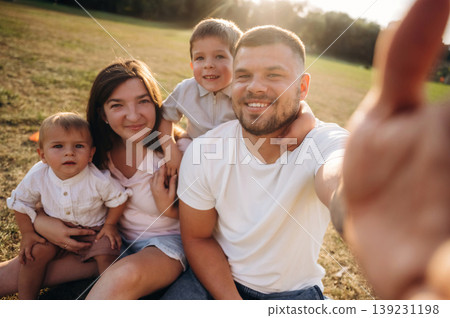 Selfie time, sitting. Mother, amputee father with prosthesis and kids are on the field Selfie time, sitting. Mother, amputee father with prosthesis and kids are on the field 139231198