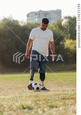 Strong amputee man with prosthesis is with soccer ball on the field Strong amputee man with prosthesis is with soccer ball on the field 139231199