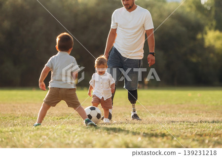Dad on prosthesis is playing soccer with his two young sons Dad on prosthesis is playing soccer with his two young sons 139231218