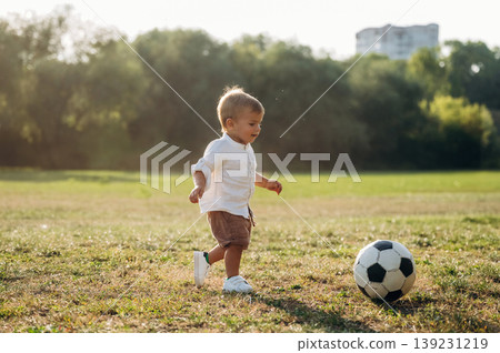 Little boy is playing soccer on the field under the sunlight Little boy is playing soccer on the field under the sunlight 139231219