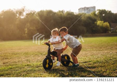 Learning to ride. Kids are playing with bicycle on the field Learning to ride. Kids are playing with bicycle on the field 139231221