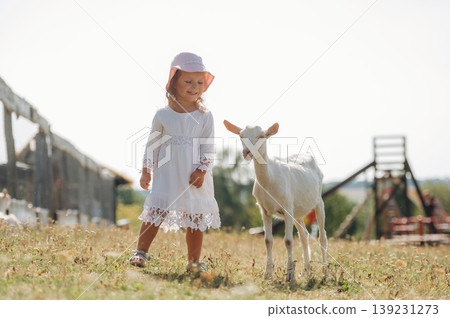 Little girl is on the goat farm outdoors at daytime 139231273