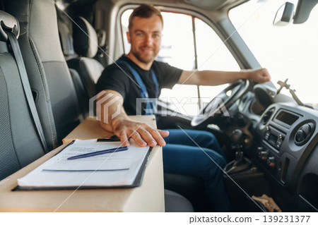 Document lying down on the box. Inside of the bus with delivery service man in uniform Document lying down on the box. Inside of the bus with delivery service man in uniform 139231377