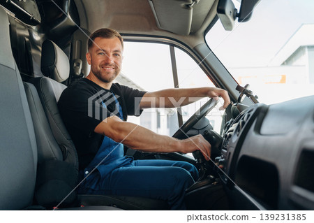 Cheerful smile, looking at the camera. Inside of the bus with delivery service man in uniform Cheerful smile, looking at the camera. Inside of the bus with delivery service man in uniform 139231385
