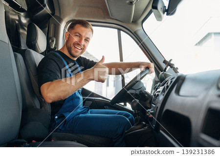 Cheerful smile, looking at the camera. Inside of the bus with delivery service man in uniform Cheerful smile, looking at the camera. Inside of the bus with delivery service man in uniform 139231386