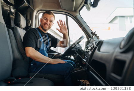 Cheerful smile, looking at the camera. Inside of the bus with delivery service man in uniform Cheerful smile, looking at the camera. Inside of the bus with delivery service man in uniform 139231388
