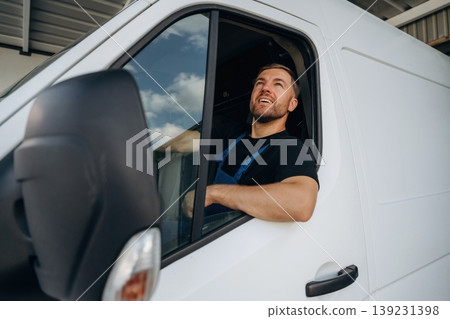 Sitting in a van and smiling. Courier of delivery service company is at work Sitting in a van and smiling. Courier of delivery service company is at work 139231398