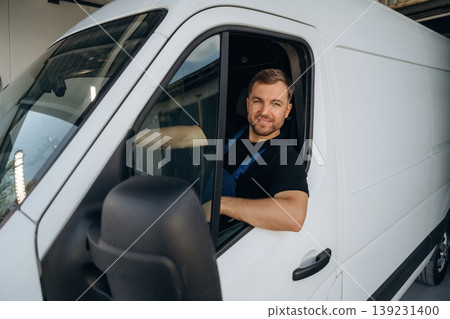 Sitting in a van and smiling. Courier of delivery service company is at work 139231400
