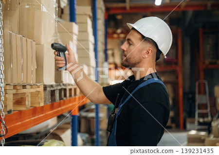 Scanning the boxes. Man in uniform is working in the storage with packages for shipment 139231435