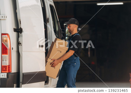 A lot of boxes. Delivery man is by the bus near garage outdoors 139231465