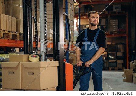 Man in uniform is working in the storage with packages for shipment Man in uniform is working in the storage with packages for shipment 139231491