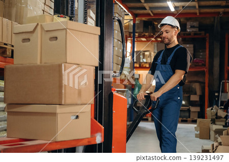 Transporting the boxes by using forklift. Man in uniform is working in the storage with packages for shipment 139231497