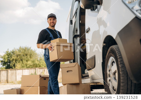 Guy courier is near the van, holding the packages Guy courier is near the van, holding the packages 139231528