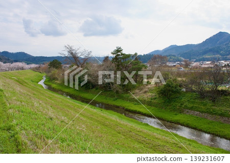 A rural landscape with a small river flowing through it. A rural landscape with a small river flowing through it. 139231607
