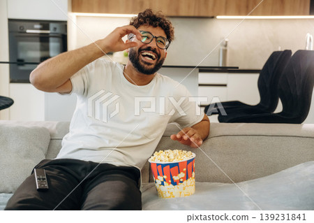 Watching a movie, with popcorn. Man is in the modern domestic room at home Watching a movie, with popcorn. Man is in the modern domestic room at home 139231841