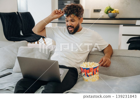 Watching a movie, with popcorn. Man is in the modern domestic room at home Watching a movie, with popcorn. Man is in the modern domestic room at home 139231843
