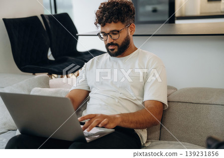 On the sofa with laptop. Man is in the modern domestic room at home On the sofa with laptop. Man is in the modern domestic room at home 139231856