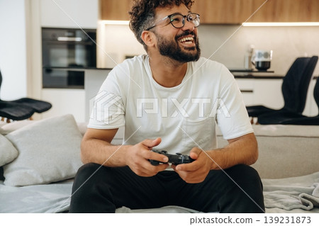 Gamer is with controller in hands. Man is in the modern domestic room at home Gamer is with controller in hands. Man is in the modern domestic room at home 139231873