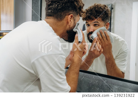 Applying shaving cream. Guy is in the bathroom, taking care of his appearance Applying shaving cream. Guy is in the bathroom, taking care of his appearance 139231922