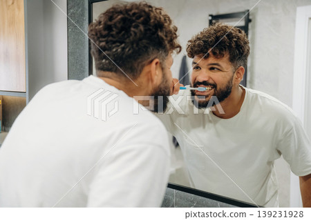 Process of brushing the teeth. Guy is in the bathroom, taking care of his appearance Process of brushing the teeth. Guy is in the bathroom, taking care of his appearance 139231928