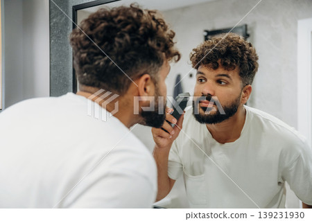 Process of brushing the teeth. Guy is in the bathroom, taking care of his appearance Process of brushing the teeth. Guy is in the bathroom, taking care of his appearance 139231930