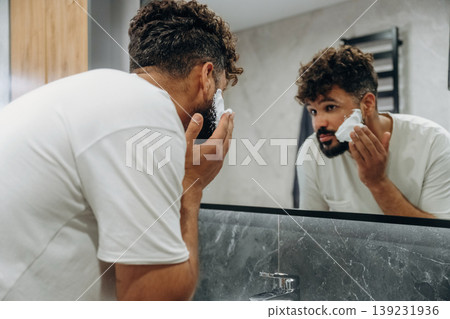 Applying shaving cream. Guy is in the bathroom, taking care of his appearance 139231936