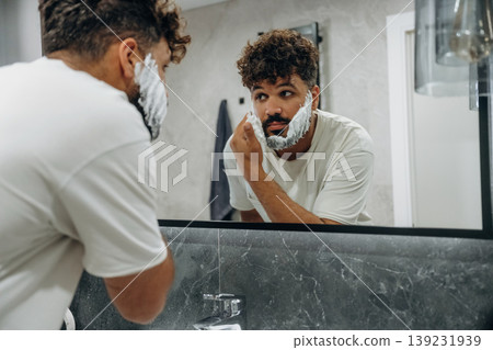 Applying shaving cream. Guy is in the bathroom, taking care of his appearance 139231939