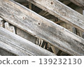 Close-up of weathered wooden beams arranged diagonally, showing aged texture, cracks, and rustic character of an old structure. 139232130
