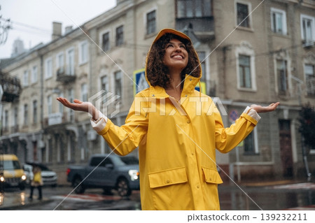 Looking up, hands to the sides. Happy young woman in the city during the rain 139232211